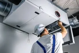 Technician servicing a ceiling-mounted air handling unit