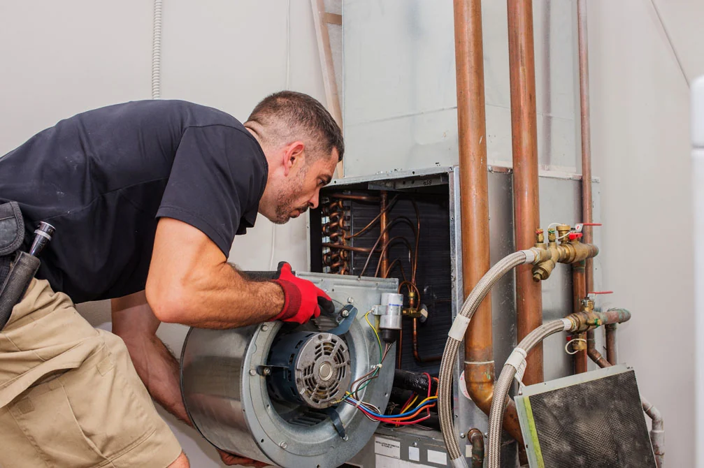 Technician inspecting the blower assembly of a home heating system